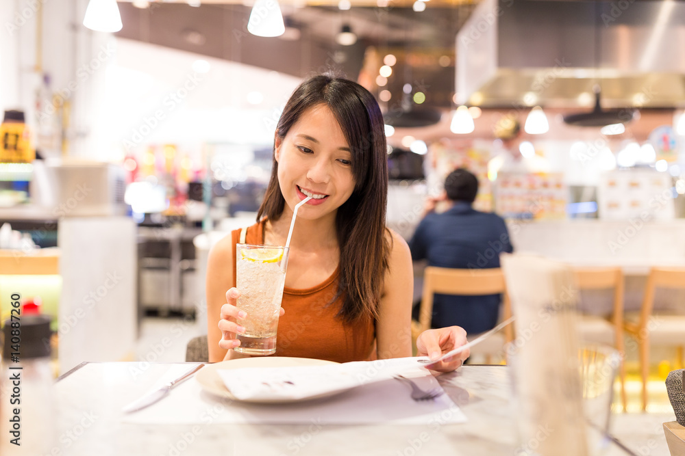 Poster Woman enjoy her drink and selecting food on menu