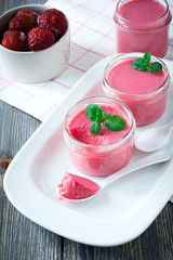 Strawberry mousse in glass jars and frozen strawberries on an old wooden table background. Selective focus.