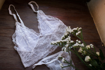 White women's lingerie and white flowers on the wooden windowsill 
