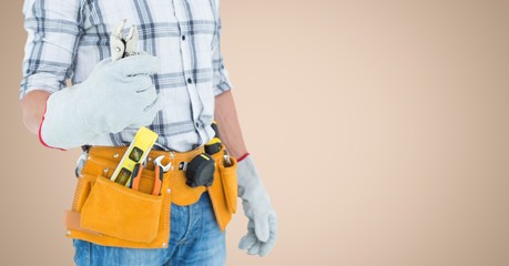 Handy man standing with tools against beige background