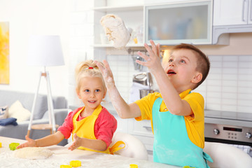 Cute little children making dough for Easter cookies