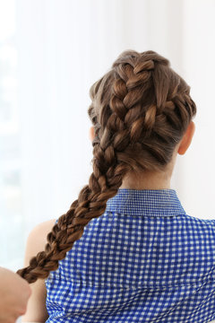 Hairdresser making braid hairstyle to young beautiful woman, closeup