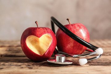 Red apples and stethoscope on wooden table