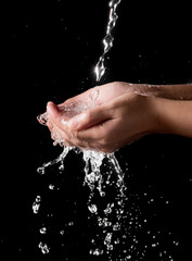 Fototapeta premium Hand and splashing water on black background