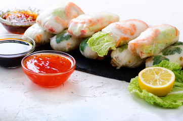 Vietnamese spring rolls - rice paper, lettuce, salad, vermicelli, noodles, shrimps, fish sauce, sweet chili, soy, lemon, veletables. Copy space. Asian and thai food. Traditional national cuisine.