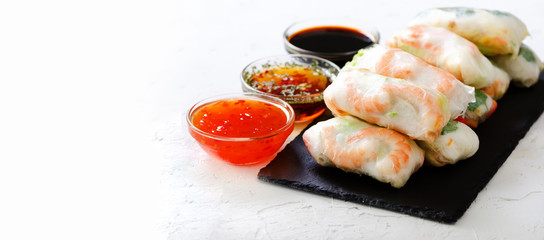 Vietnamese spring rolls - rice paper, lettuce, salad, vermicelli, noodles, shrimps, fish sauce, sweet chili, soy, lemon, veletables. Copy space. Asian and thai food. Traditional national cuisine.