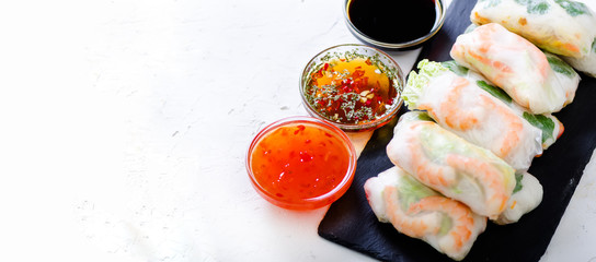 Vietnamese spring rolls - rice paper, lettuce, salad, vermicelli, noodles, shrimps, fish sauce, sweet chili, soy, lemon, veletables. Copy space. Asian and thai food. Traditional national cuisine.