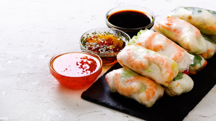 Vietnamese spring rolls - rice paper, lettuce, salad, vermicelli, noodles, shrimps, fish sauce, sweet chili, soy, lemon, veletables. Copy space. Asian and thai food. Traditional national cuisine.