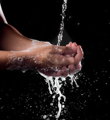 Fototapeta na wymiar Washing of hands with splashing water on black background