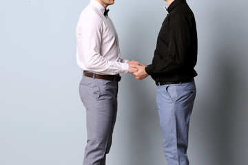 Happy gay couple holding hands together on color background