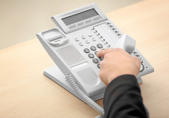 Hand of man dialing telephone number in office