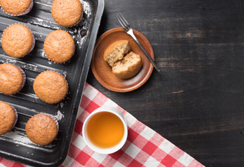 banana cup cake in a baking tray and tea on wood,top view