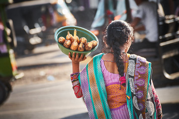 Nepalese woman carries a basket with roasted corn on the street 