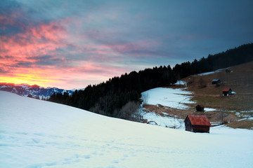 dramatic sunset over snowy mountains and huts