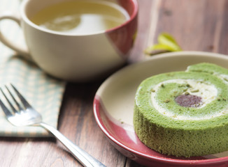 Green tea cake roll and hot green tea matcha on wood background
