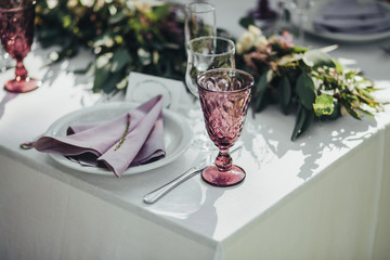 Festive table served dishes and decorated with branches of greenery, stands on green grass in the area of wedding party