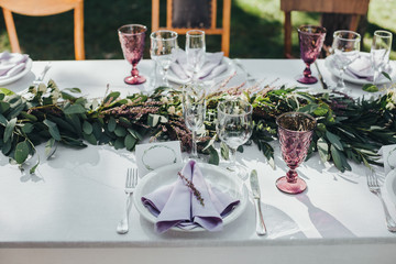 Festive table served dishes and decorated with branches of greenery, stands on green grass in the...