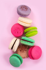Multicolored macaroon cookies on a pink background