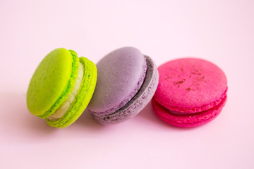 Multicolored macaroon cookies on a pink background