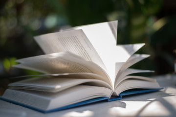 Open book on a white table in the garden.