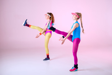 Fototapeta na wymiar young sporty women doing aerobic exercises on pink