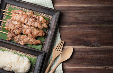 Thai styled grilled pork and sticky rice on wood