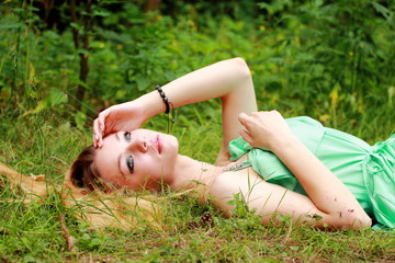 Emotional blonde, dreaming, looking in the sky, lying on the grass.
