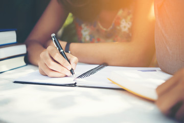 Woman writing on notebook while working at office.
