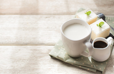 glass of milk and milk cake delicious on the wood table with shadows from a window frame