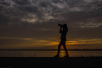 Woman holding a camera on sunset