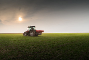Fototapeta premium Tractor spreading artificial fertilizers