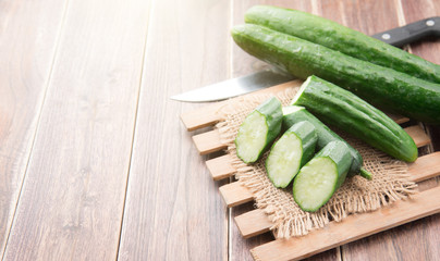 Cucumber and slices on wood background.