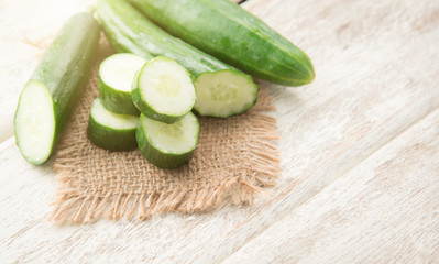 Cucumber and slices on wood background.