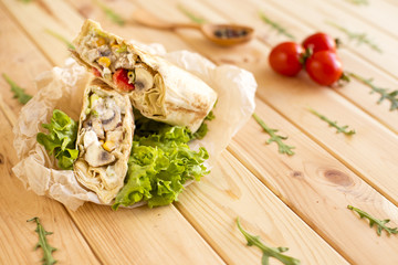 Burritos wraps with meat chicken beans and vegetables on wood board