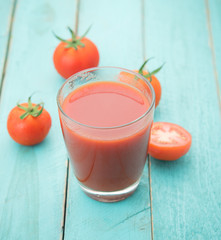 Glass of tomato juice on blue wooden table