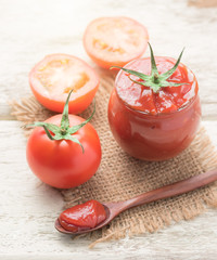 Tomato sauce, ketchup in glass jar on wood background