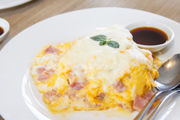 Delicious hot jusmine rice topping with omelette with ham or minced pork in omelette serve on white plate and on white wooden table