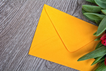 Envelope and tulip on a wooden background