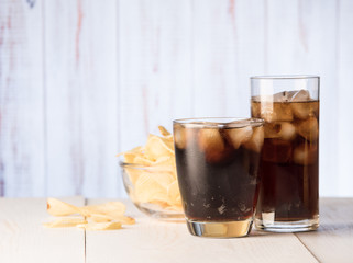 Cola glass with potato chips on a wood