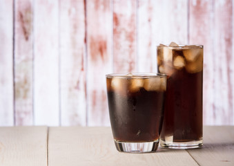 Cola in glass with ice on wood background