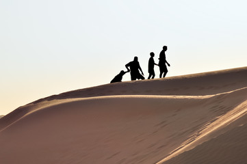 Silhouette of Family Climbing Sand Dune