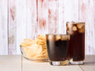 Cola glass with potato chips on a wood
