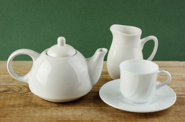 white ceramic coffee set on old wooden table over green background