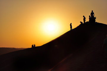 People Silhouetted On A Desert Dune