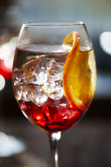 Close view at refreshing red cocktail with orange bokeh background