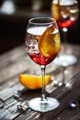refreshing red cocktails with orange isolated on a wooden background with oranges and ice