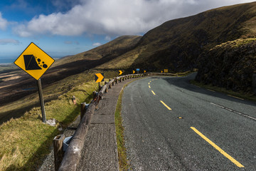 Narrow winding road and falling rocks sign at the top of the Connor pass on the Dingle peninsula, County Kerry, Ireland