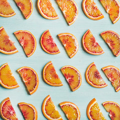 Natural fruit pattern concept. Fresh juicy blood orange slices over light blue painted table background, top view, square crop