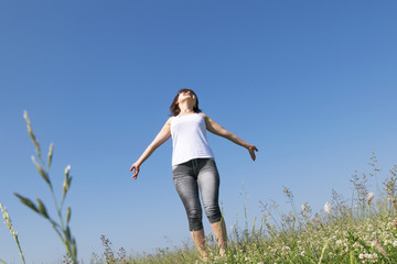 Beautiful brunette girl in a summer field of flowers is charged with energy
