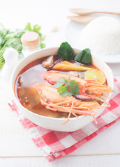 Tom Yam Kung (Thai cuisine) with rice on table wooden